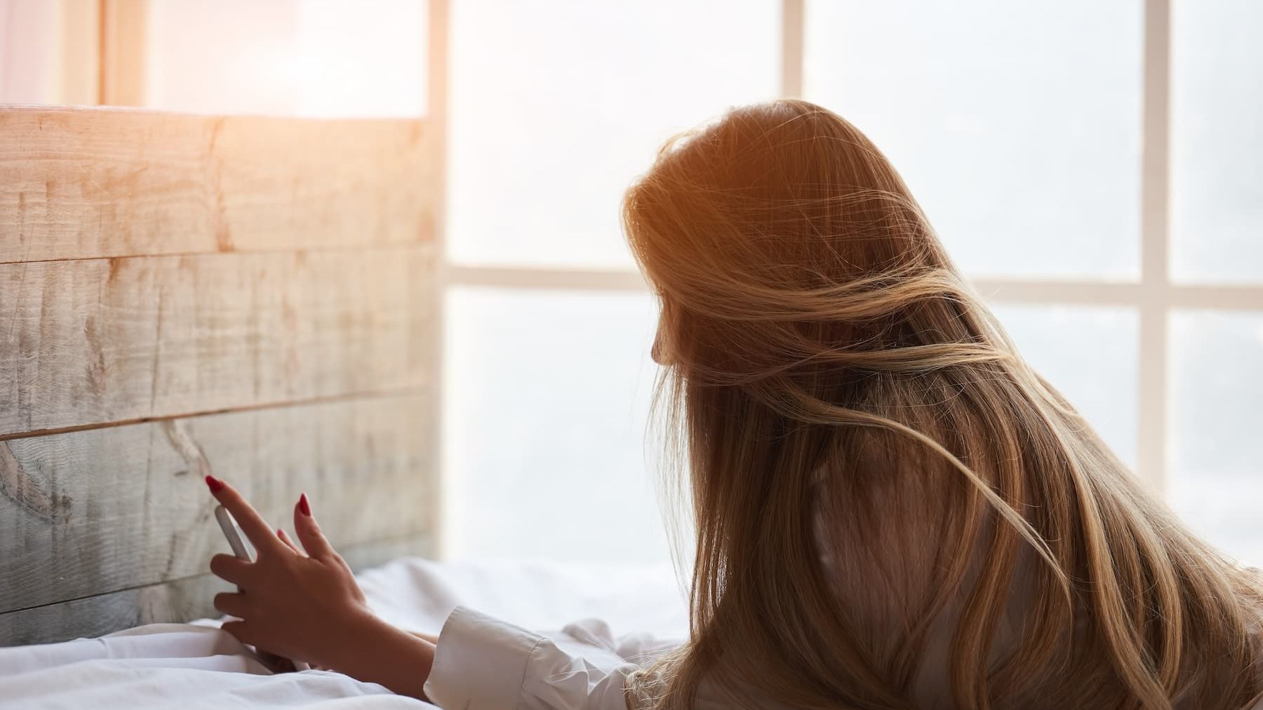 Woman in bed holding her phone in the morning.